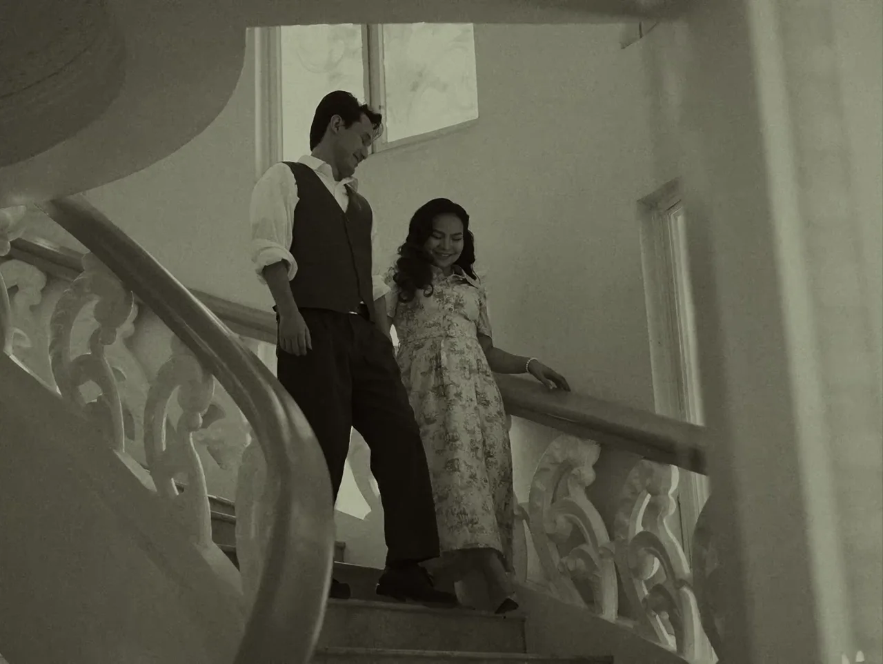 James and Elaine descending a grand staircase, in black and white
