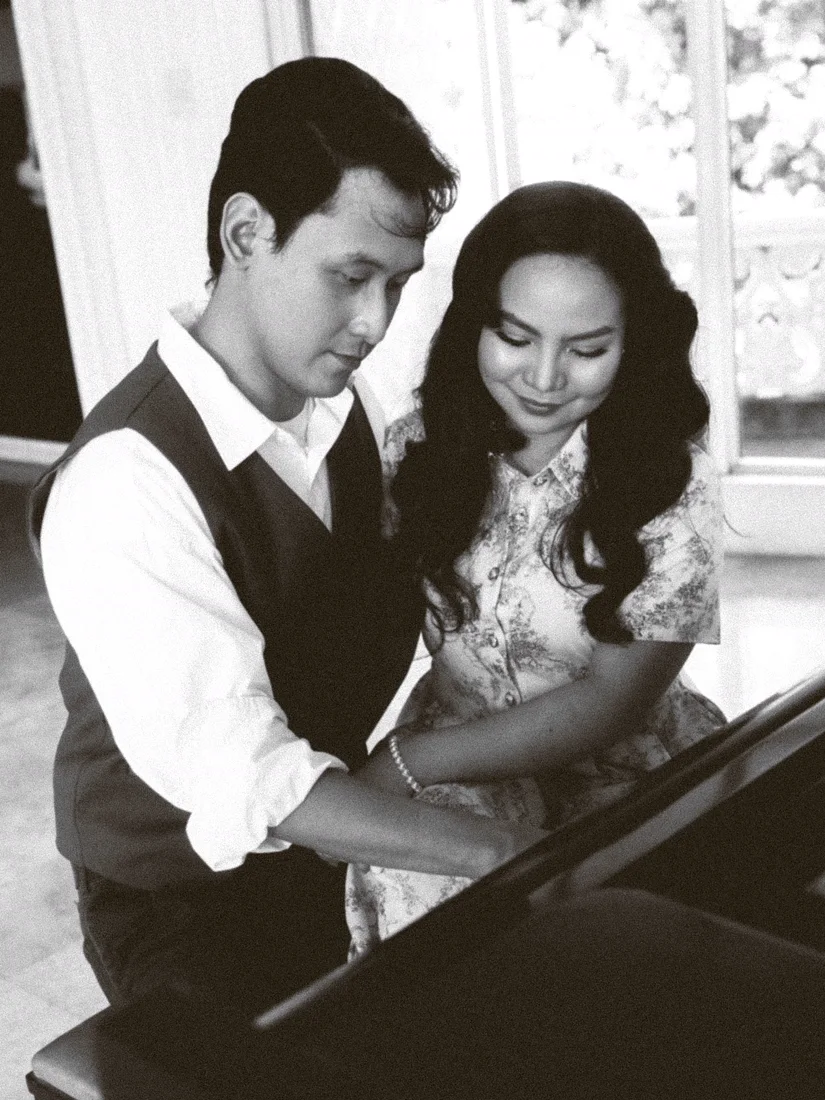 James and Elaine close together at the piano, in black and white