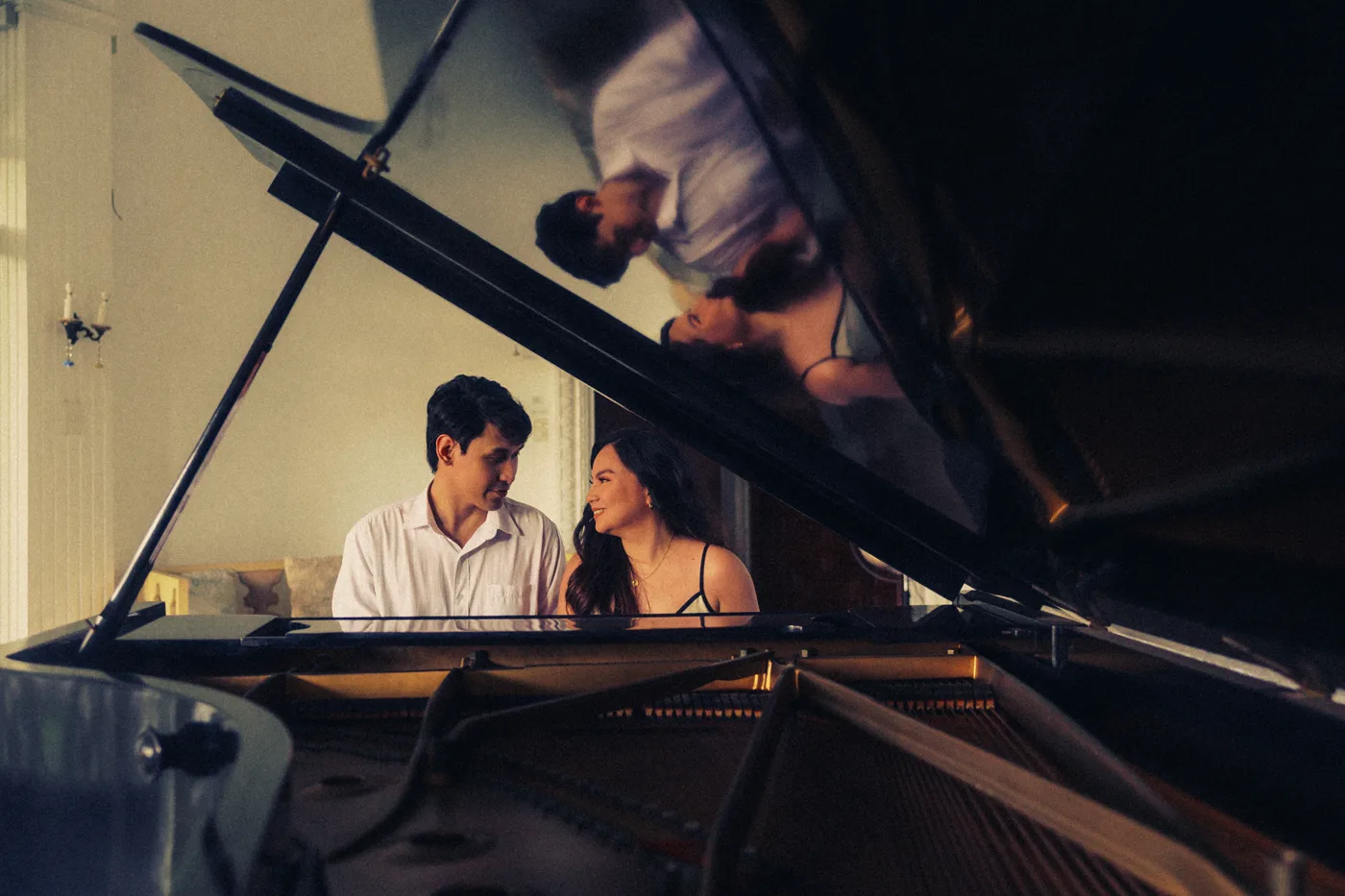 James and Elaine playing the grand piano together, reflected in its lid