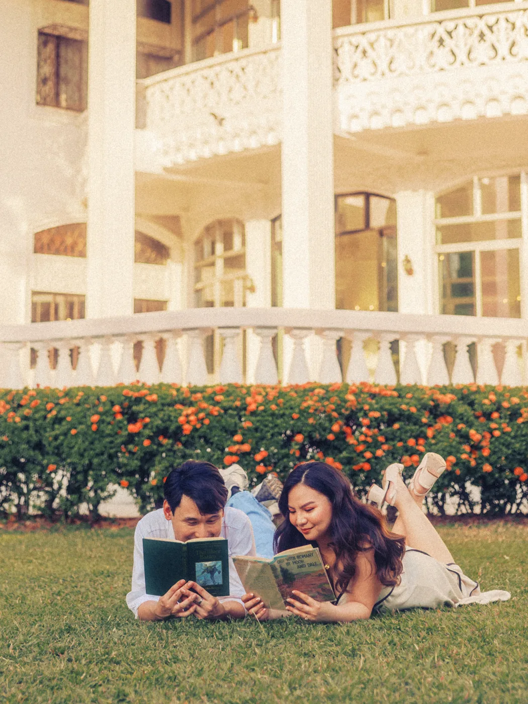 James and Elaine lying on the grass, reading one book together